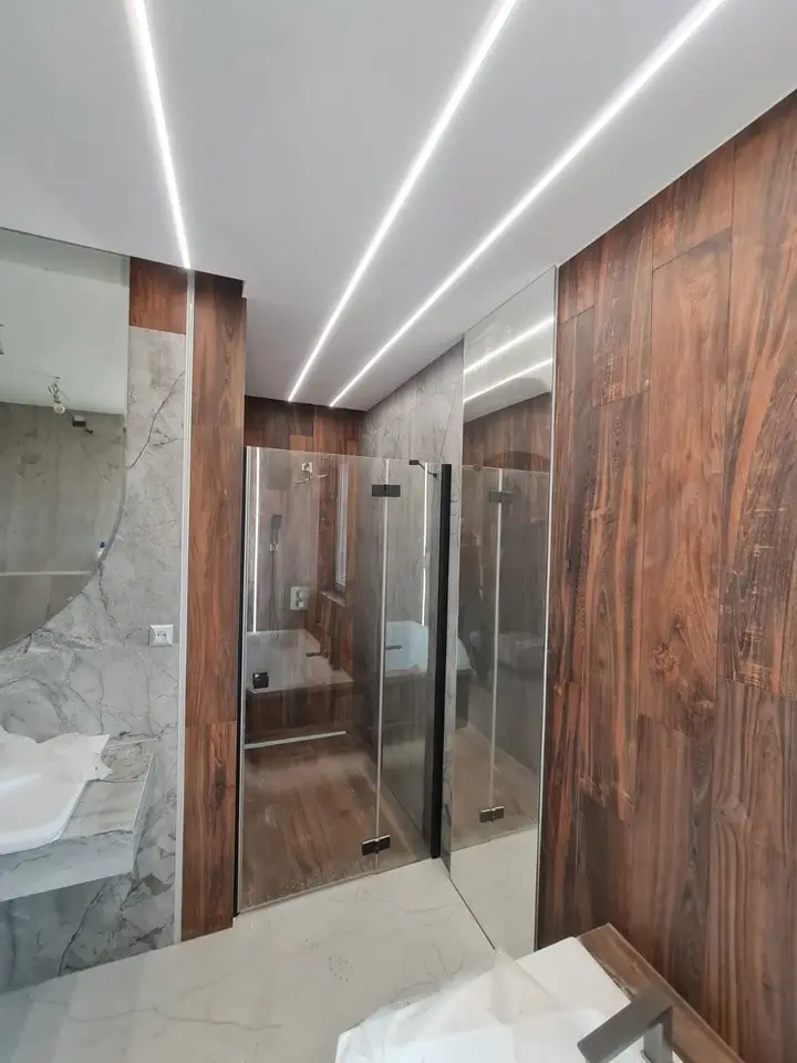 Wykończona przez SB House łazienka, ledy na suficie, drewniany motyw na ścianach, szklany prysznic