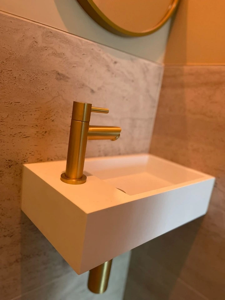 Umywalka wisząca na ścianie. Piękny, złoty kran, wiszące na nią lustro